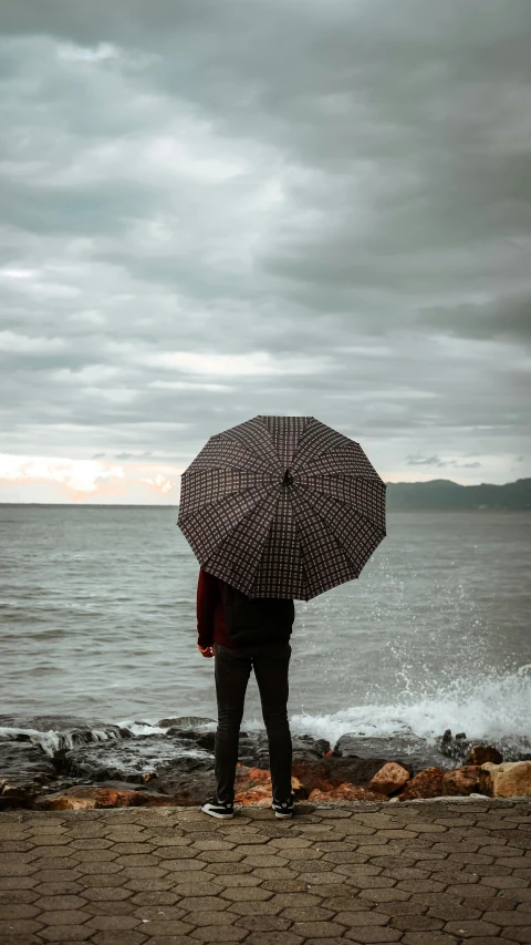 a person standing on a beach holding an umbrella, unsplash contest winner, renaissance, gazing at the water, foreboding sea, brown, polka dot