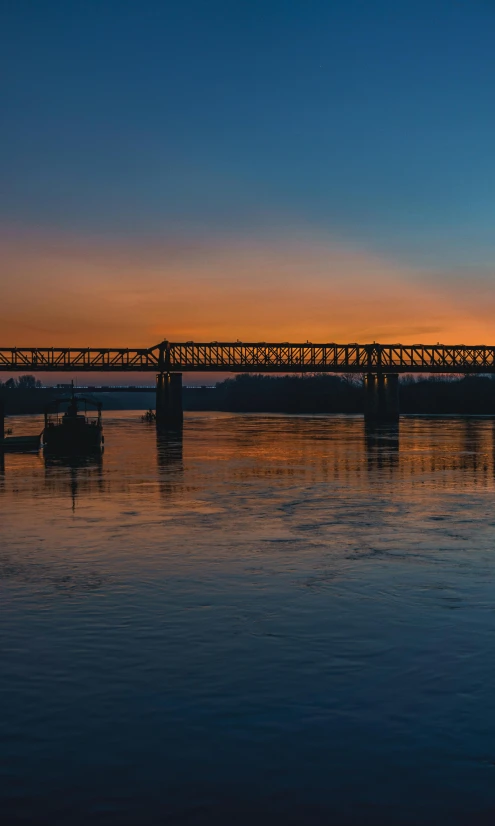 a train crossing a bridge over a body of water, at the golden hour, panoramic, golden hour photograph, ballard