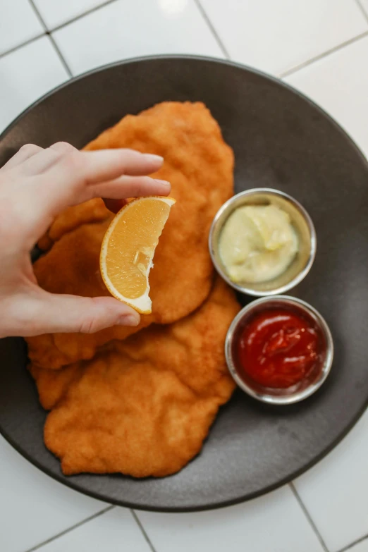 a person holding a slice of lemon over a plate of food, battered, lion's mane, sleek hands, orange