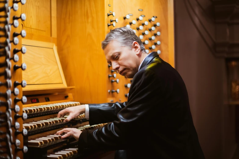 a man in a suit playing a pipe organ, profile image