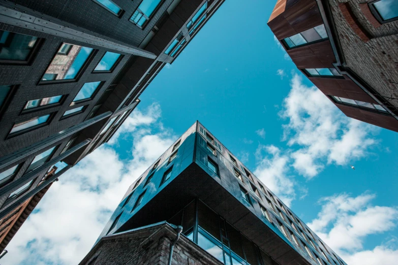 a group of tall buildings sitting next to each other, a photo, unsplash, modernism, blue sky above, wooden buildings, looking downwards, buildings covered in black tar