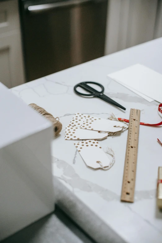 a pair of scissors sitting on top of a counter, pexels contest winner, arts and crafts movement, labels, paper decoration, white marble interior photograph, holiday