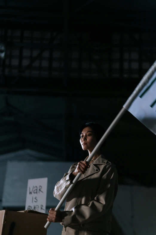 a woman holding a black and white flag, projection mapping, stood in a factory, jakarta, ( ( theatrical ) )