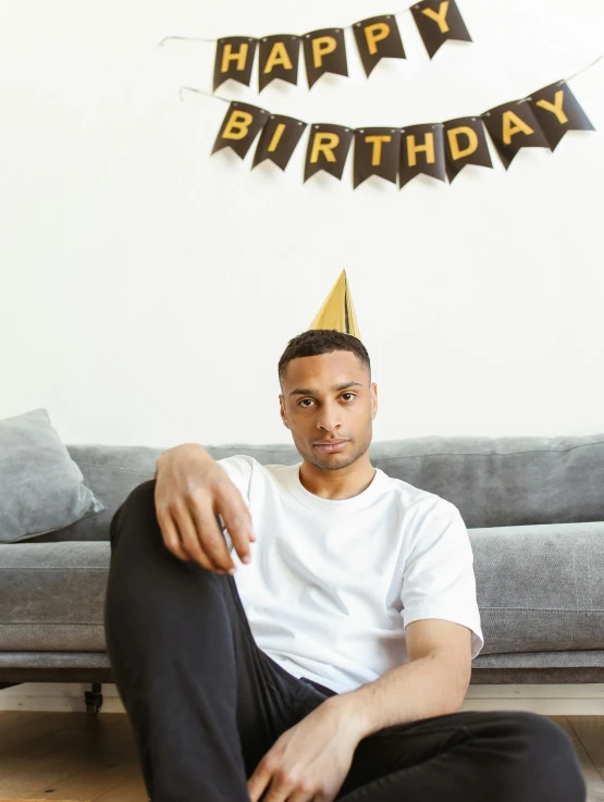 a man sitting on the floor wearing a party hat, trending on unsplash, renaissance, lean man with light tan skin, black man, happy birthday, ( ( theatrical ) )