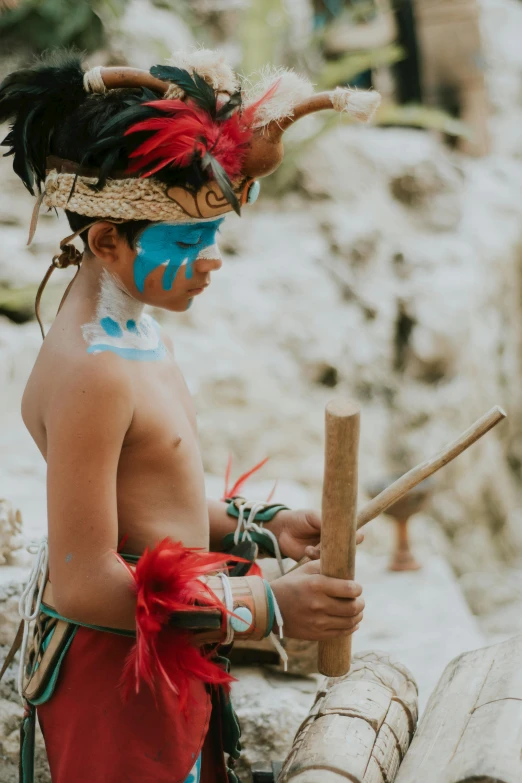 a young boy dressed in native clothing holding a stick, an album cover, pexels contest winner, mayan, preparing for battle, cave painting, ceremonial ritual