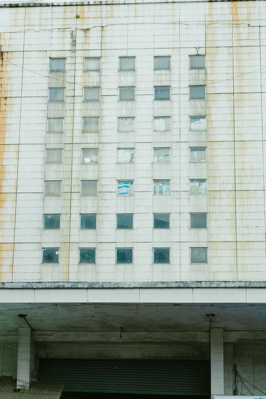 a car that is parked in front of a building, an album cover, inspired by Zhang Kechun, unsplash, brutalism, window ( city ), medical research facility, water stains, pyongyang city