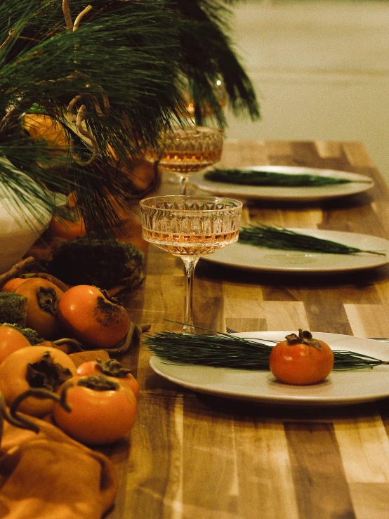 a wooden table topped with plates of food, evergreen branches, profile image, orange details, thumbnail