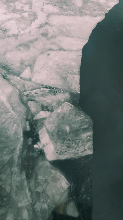 a man standing on top of a pile of ice, inspired by Elsa Bleda, unsplash, lyrical abstraction, close-up from above, half face in the water, gray stone, grainy footage