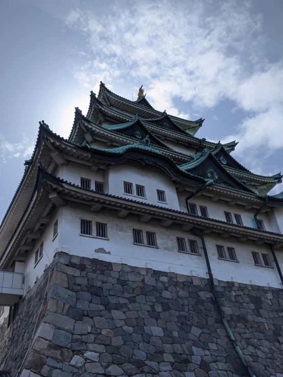 a tall building sitting on top of a stone wall, inspired by Kōshirō Onchi, unsplash, sōsaku hanga, ornate palace made of green, 2 0 0 0's photo, けもの, turrets