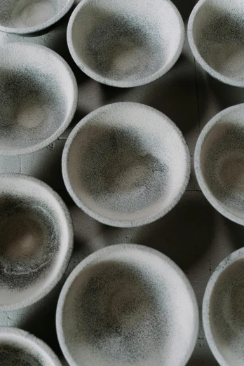a group of white bowls sitting on top of a table, inspired by Maruyama Ōkyo, trending on unsplash, concrete art, gradient black to silver, high angle close up shot, woodfired, in a row