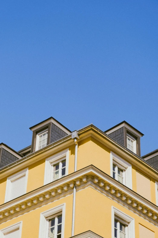 a clock that is on the side of a building, an album cover, inspired by Albert Paris Gütersloh, unsplash, neoclassicism, yellow color scheme, simple gable roofs, profile image, clear blue skies