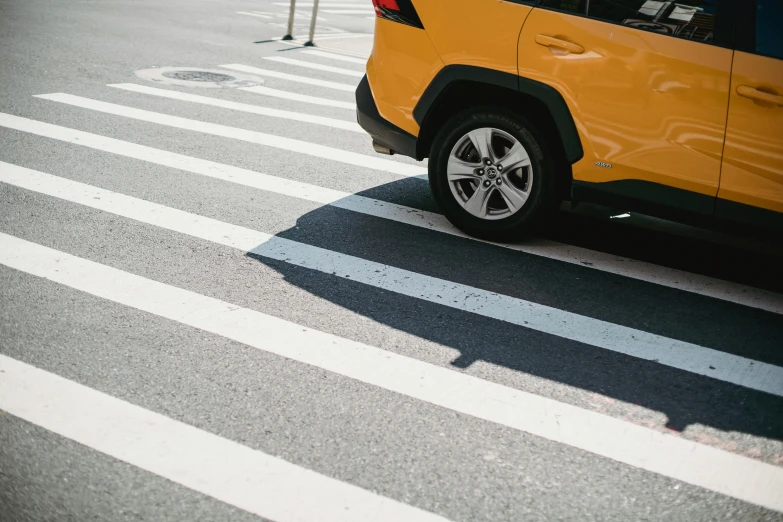 a yellow jeep driving down a street next to a crosswalk, by Adam Marczyński, unsplash contest winner, photorealism, square lines, street of new york, closeup photograph, full view of a car