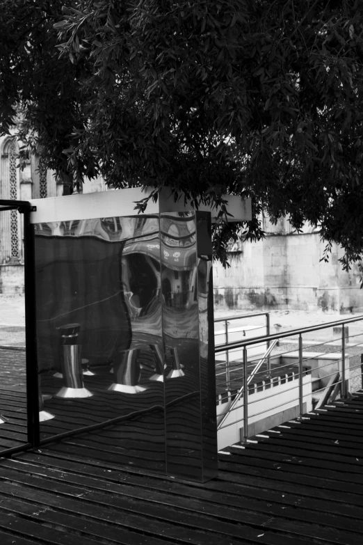 a black and white photo of a bus stop, inspired by André Kertész, temporary art, mirror and glass surfaces, at the terrace, fountain in the middle, monochrome:-2