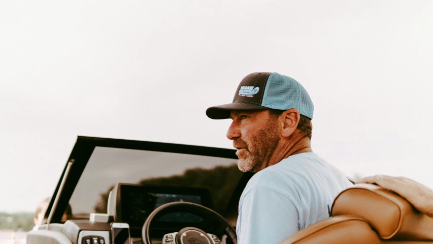 a man sitting in the driver's seat of a boat, sleek blue visor for eyes, cool dad vibes, thumbnail, profile shot