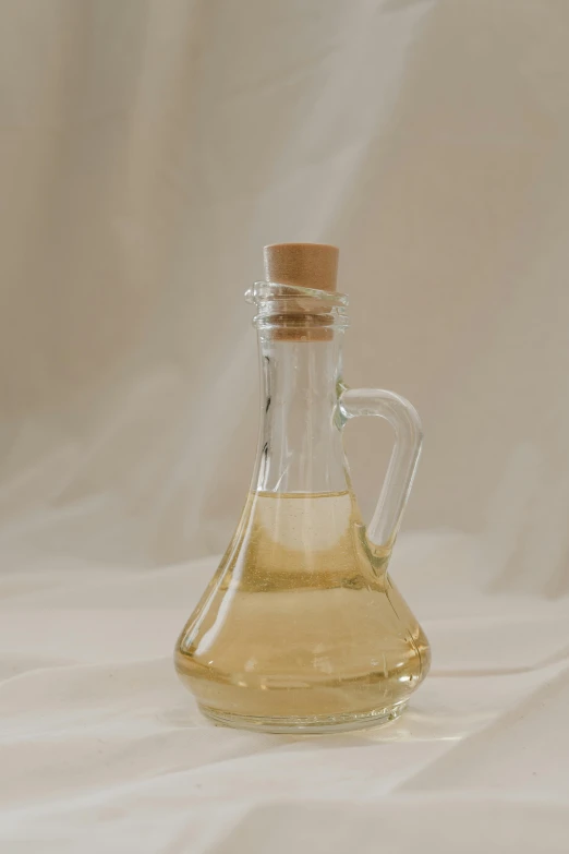 a bottle of oil sitting on top of a table, product image, on a pale background, clear glass, traditional medium