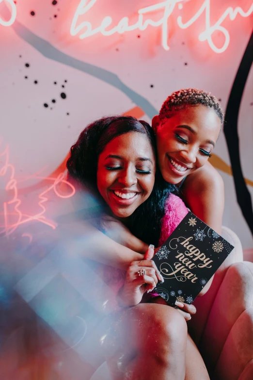 two women hugging each other in front of a neon sign, a portrait, trending on pexels, happening, holding a book, new years eve, black teenage girl, flatlay book collection