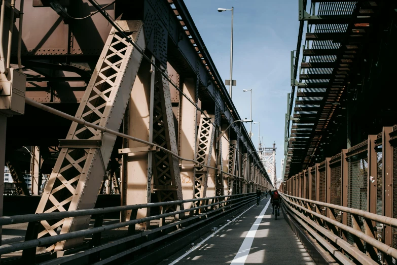 a person riding a bike on a bridge, an album cover, inspired by Thomas Struth, unsplash contest winner, harlem, massive structures, great light and shadows”, in the middle of new york