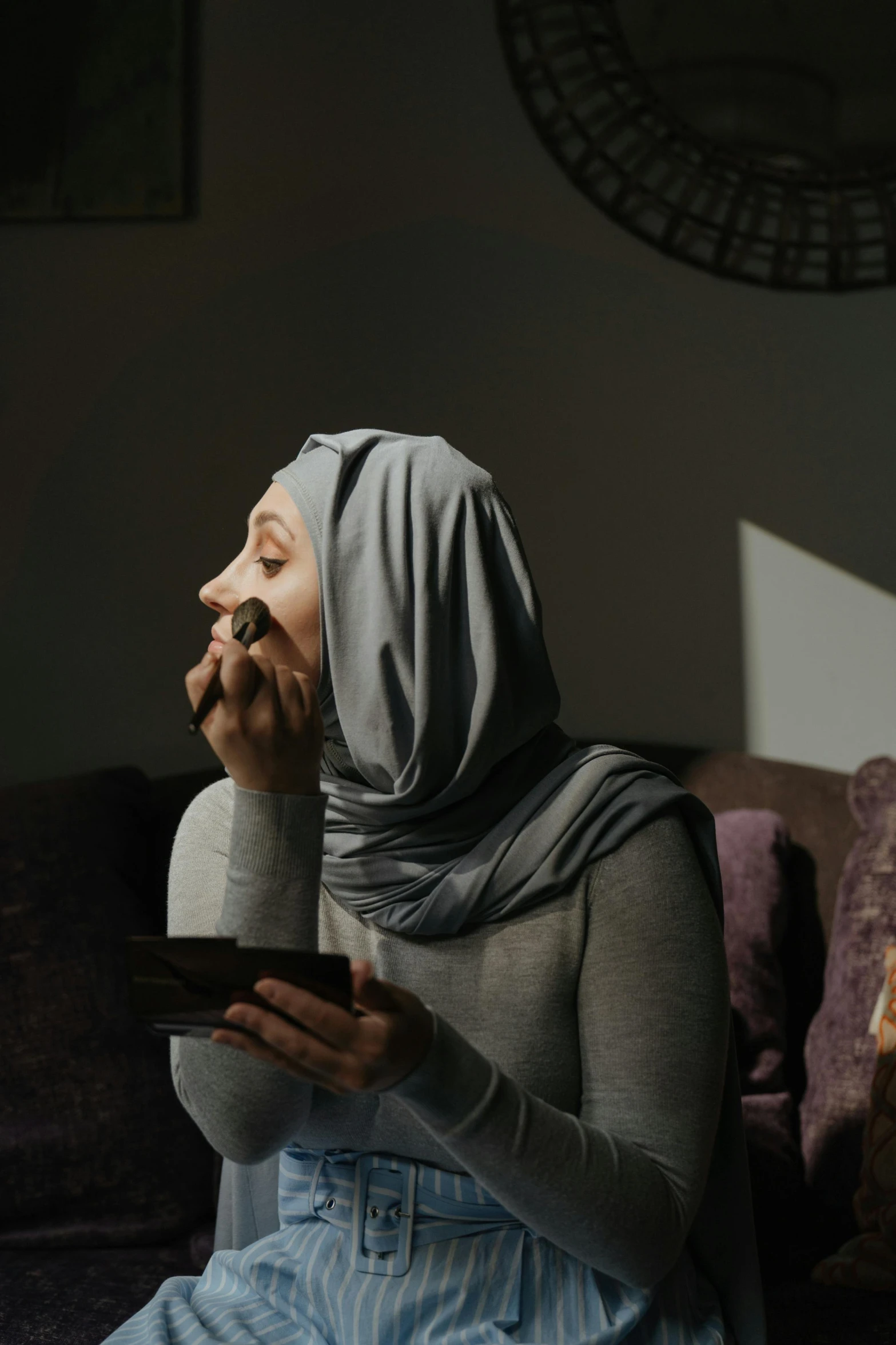 a woman sitting on a couch talking on a cell phone, inspired by Maryam Hashemi, pexels contest winner, hurufiyya, having a snack, somber expression, face covered, with grey skin