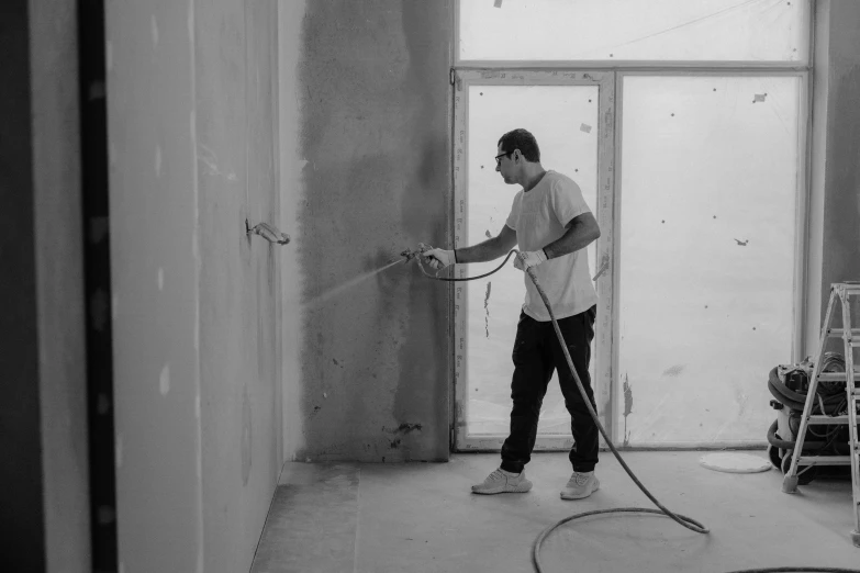 a man that is standing in a room with a hose, an airbrush painting, by Jan Kupecký, pexels contest winner, arbeitsrat für kunst, gray concrete, working, background image, smooth panelling