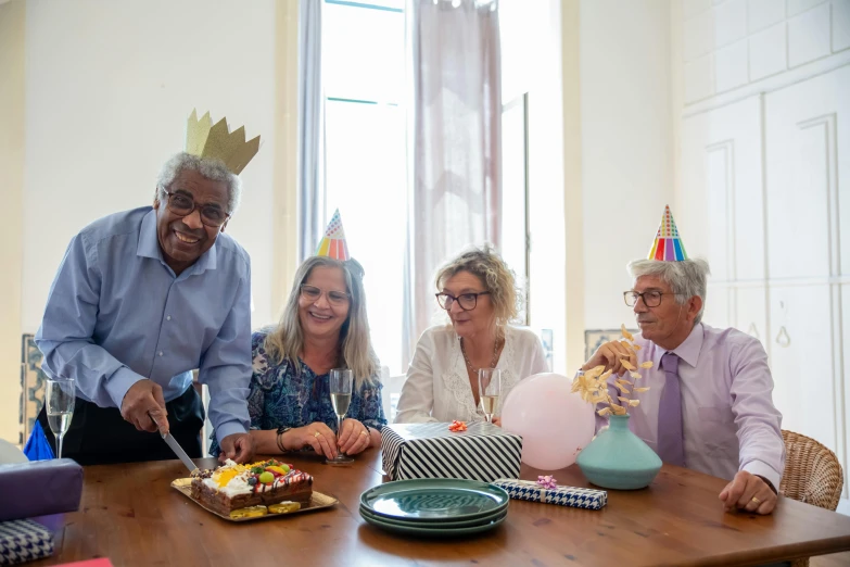 a group of people sitting around a table cutting a cake, profile image, an oldman, background image, wearing a crown