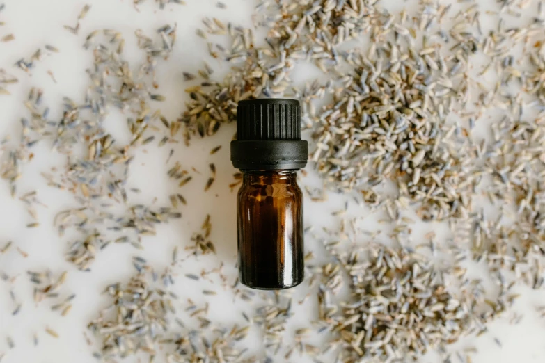 a bottle of lavender essential oil next to a pile of lavender flowers, by Carey Morris, trending on pexels, clean minimalist design, brown, grey, tiny details