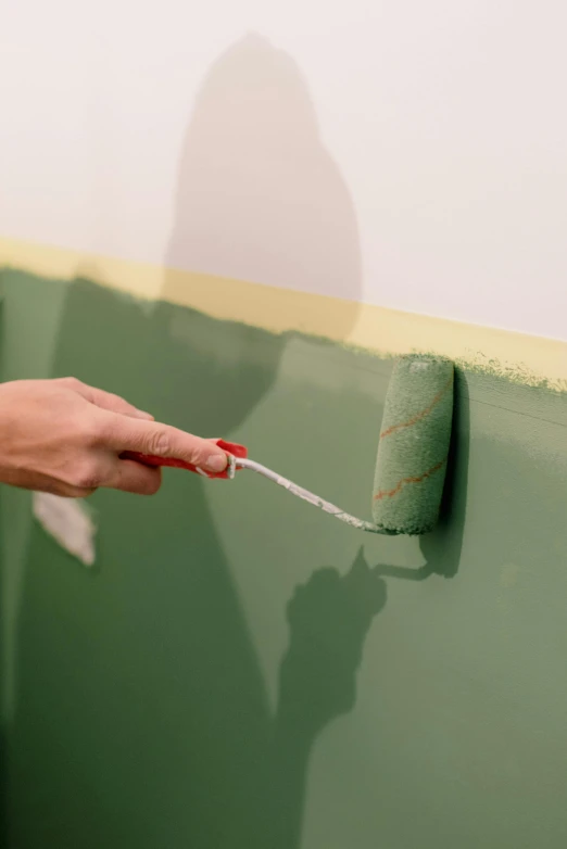 a person painting a wall with a paint roller, inspired by Clarice Beckett, trending on unsplash, muted green, clean long lines, promo image, up-close