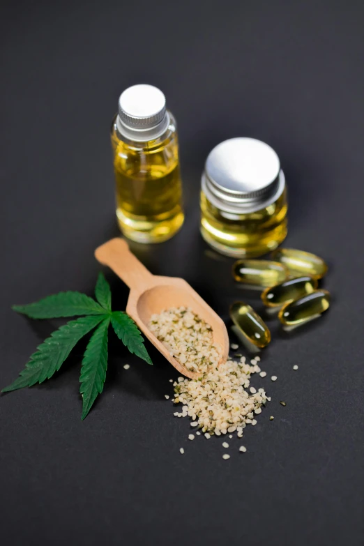 hemp oil, hemp seeds and a wooden spoon on a black surface, a picture, by Jakob Gauermann, shutterstock, pills, made of glowing oil, monaco, jets