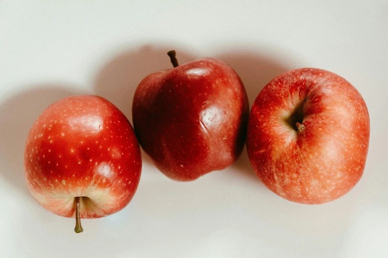 three apples sitting next to each other on a white surface, by Emma Andijewska, pexels, detailed glowing red implants, local foods, 🦩🪐🐞👩🏻🦳, profile image