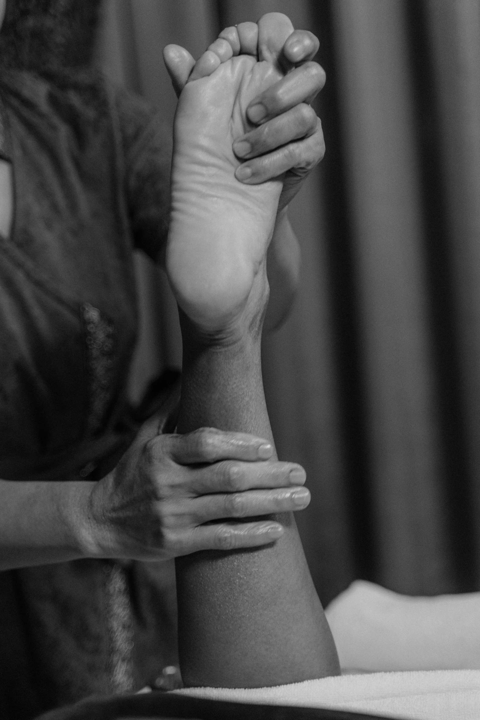 a black and white photo of a woman getting a foot massage, a black and white photo, square, stretch, holding a staff, foto