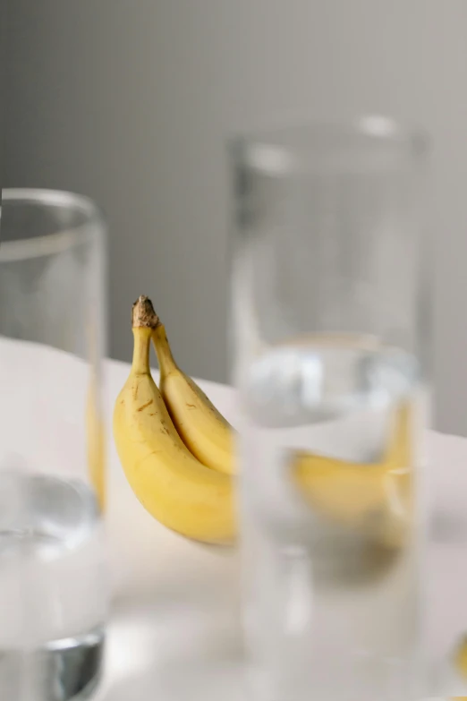 a bunch of bananas sitting on top of a table, by Nina Hamnett, unsplash, hyperrealism, glass refraction, embarrassed, drinking, minimalist