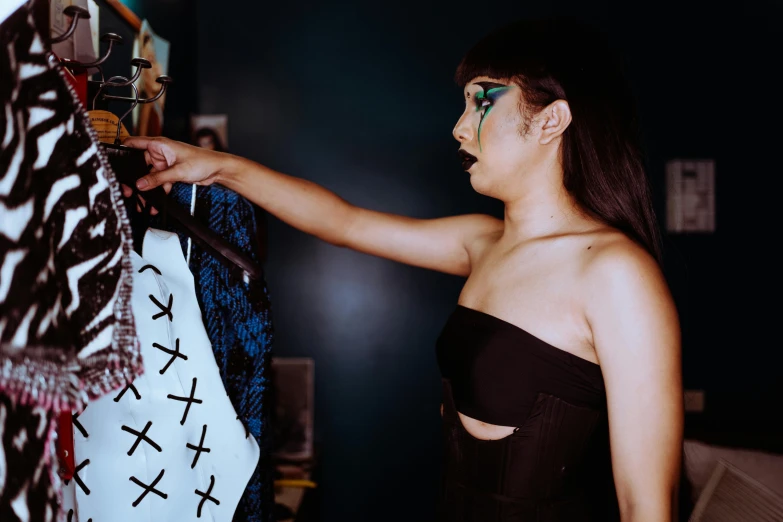 a woman standing in front of a rack of clothes, an album cover, trending on pexels, visual art, wearing atsuko kudo latex outfit, behind the scenes photo, profile image, candid portrait photo