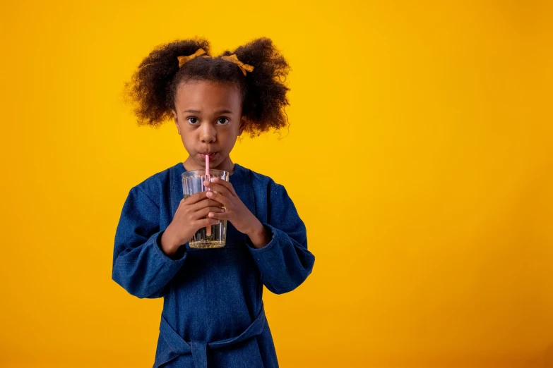 a little girl holding a glass of water, pexels, hyperrealism, afro, yellow backdrop, 1 4 9 3, drinks