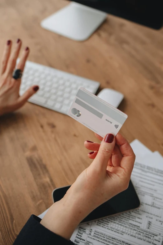 a person holding a credit card in front of a computer, by Carey Morris, pexels contest winner, square, how pretty, sitting on a table, plain background