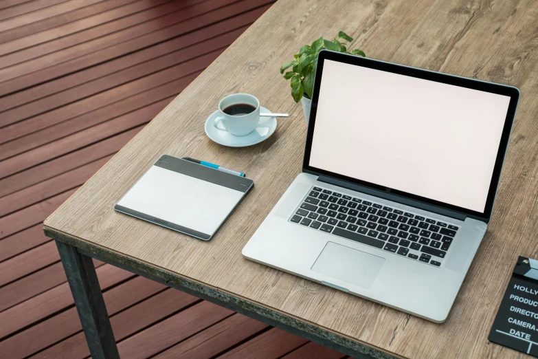 a laptop computer sitting on top of a wooden table, a computer rendering, unsplash, 9 9 designs, a handsome, blank, table in front with a cup