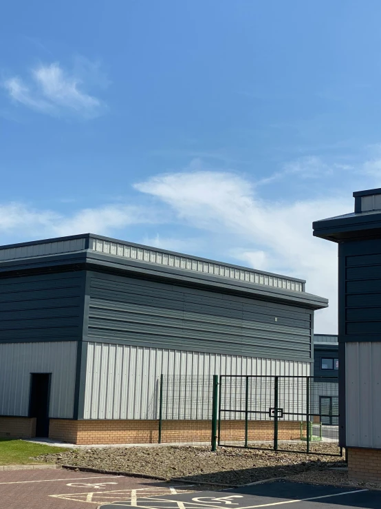 a large building sitting next to a parking lot, a cartoon, unsplash, northwest school, iron cladding, industrial colours, shot from roofline, outside enclosure