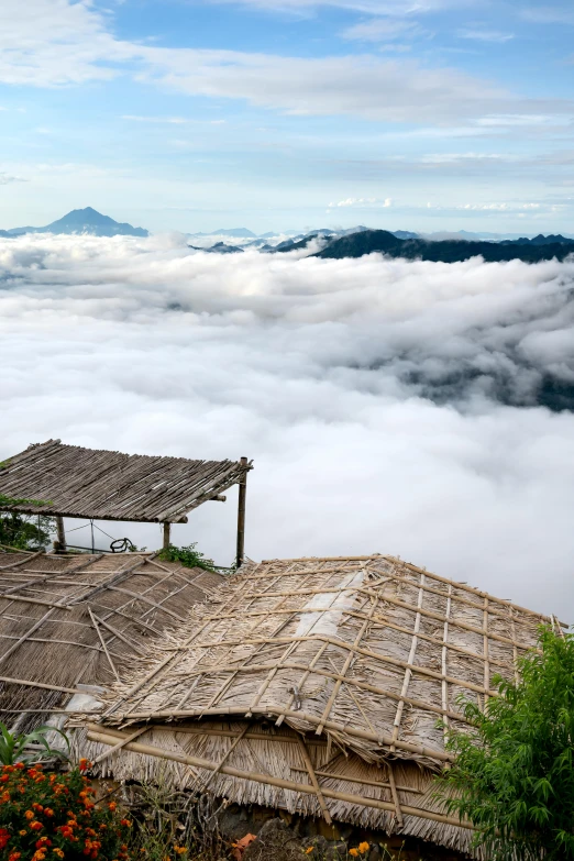 a group of huts sitting on top of a lush green hillside, sumatraism, view above the clouds, slide show, white sea cloud, multiple stories