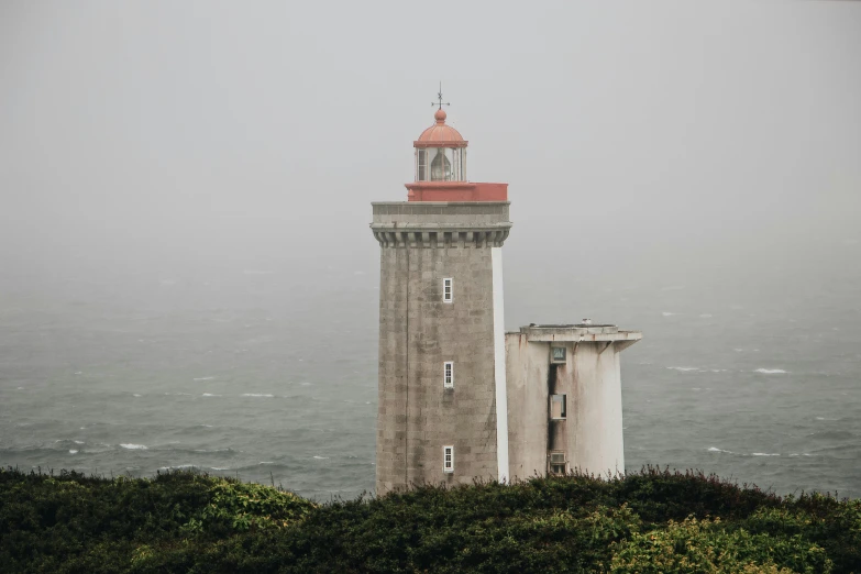 a lighthouse sitting on top of a lush green hillside, an album cover, pexels contest winner, romanticism, under a gray foggy sky, architecture photo, northern france, built on a small