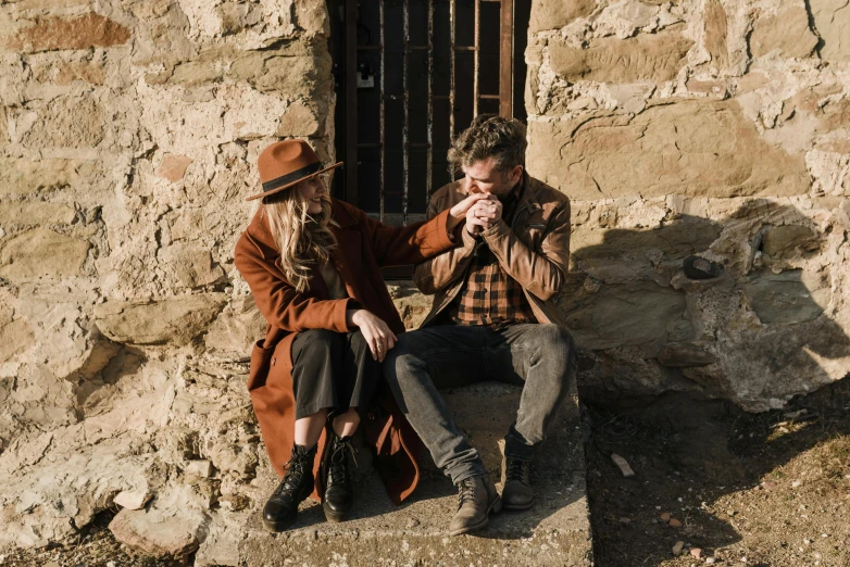 a man and a woman sitting next to each other, by Emma Andijewska, pexels contest winner, brown tuffle coat, caramel. rugged, occasional small rubble, western setting