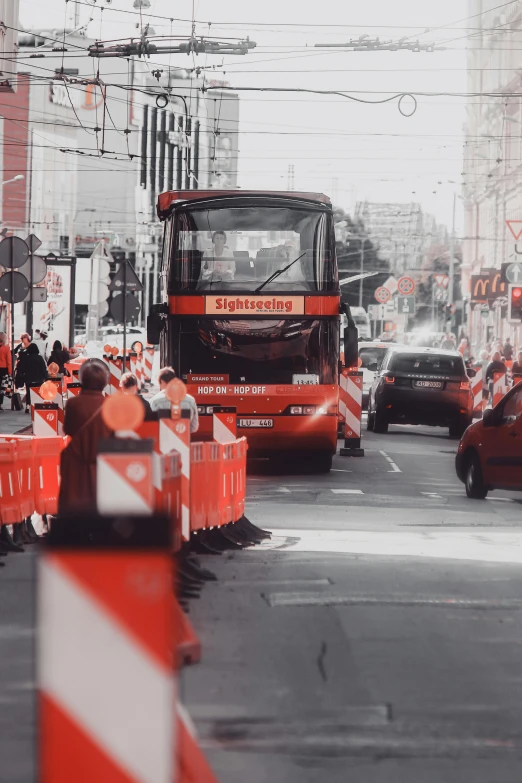 a red double decker bus driving down a city street, a picture, by Niko Henrichon, happening, under construction, worksafe. cinematic, full of people, red monochrome