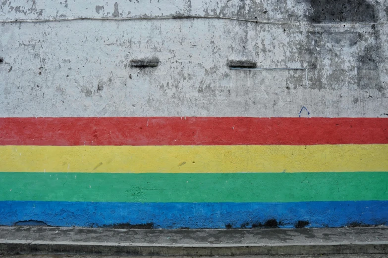 a rainbow painted on the side of a building, an album cover, inspired by Banksy, unsplash, indonesia, background image, lgbt flag, concrete wall