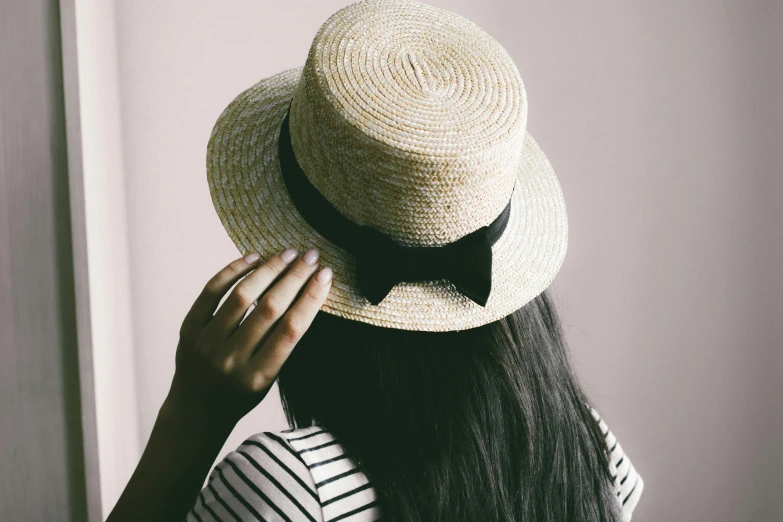 a close up of a person wearing a hat, by Julia Pishtar, trending on pexels, holding a bow, back of head, small hat, with straight black hair