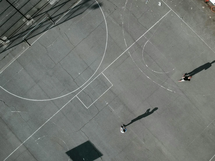 a couple of people standing on top of a basketball court, pexels contest winner, square lines, aerial footage, gray concrete, people falling off a playground