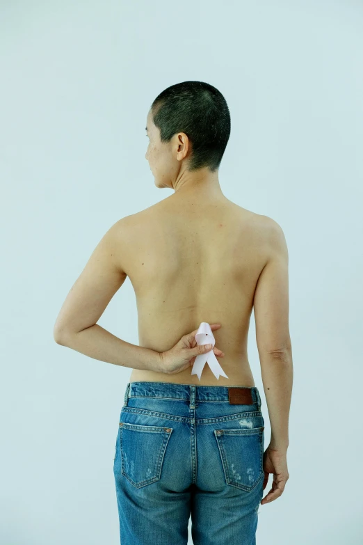a man standing with his back to the camera, inspired by Ren Hang, happening, white ribbon, non binary model, ( ( ( wearing jeans ) ) ), promo image
