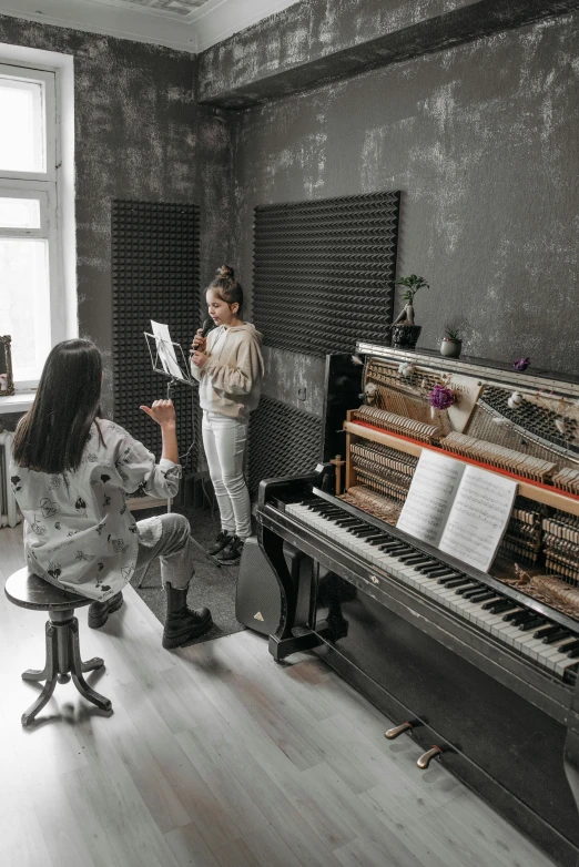 a couple of people that are sitting in front of a piano, in a room