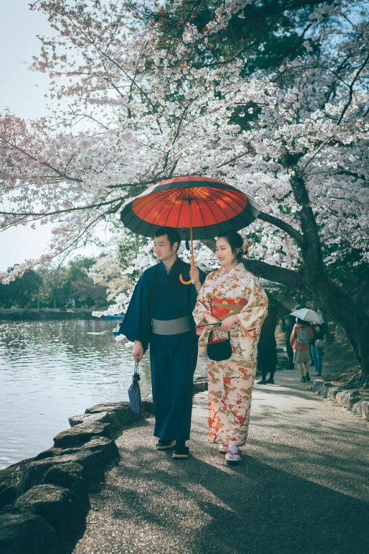 a couple of people standing next to a body of water, a picture, inspired by Kanō Shōsenin, cherry blossom trees, fujifilm”, parasols, fujicolor sample