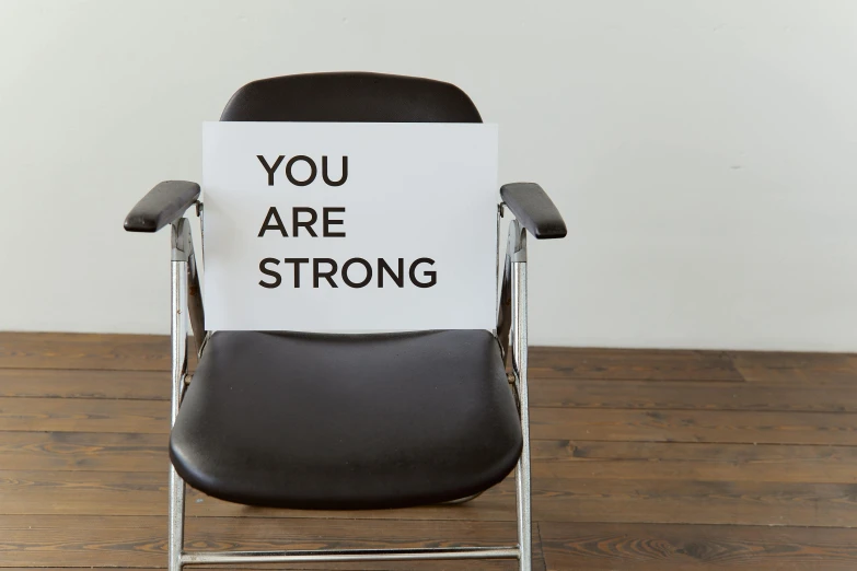 a chair with a sign that says you are strong, by Nina Hamnett, still photograph, healthcare, black, rectangle