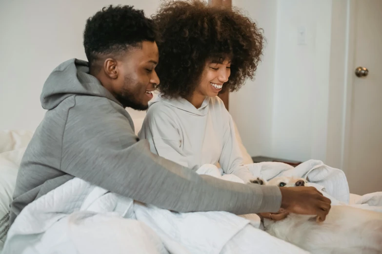 a man and woman sitting on a bed with a dog, pexels contest winner, happening, smiling couple, high quality screenshot, families playing, grey