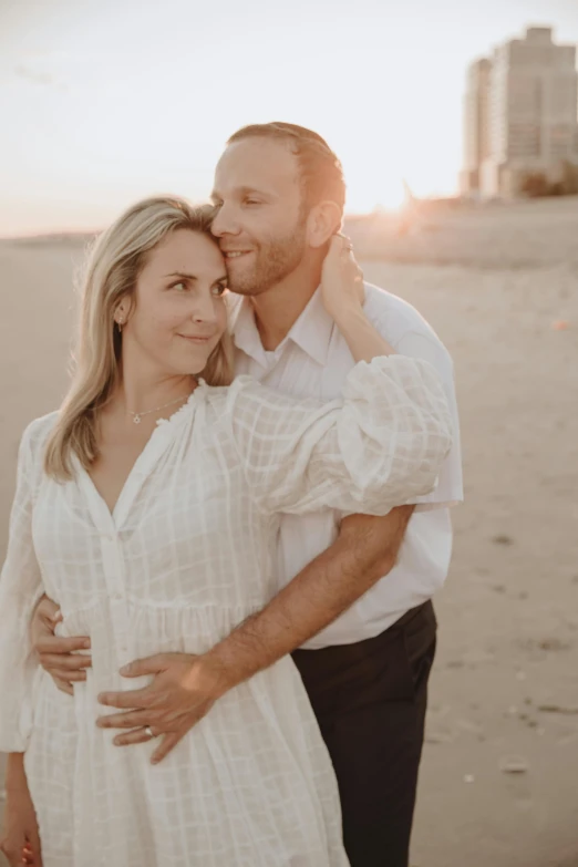 a man and woman standing next to each other on a beach, maternity feeling, wearing a white button up shirt, warm glow, blonde
