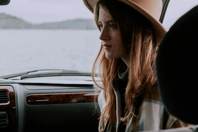 a woman sitting in a car wearing a hat, inspired by Sydney Carline, pexels contest winner, renaissance, girl with brown hair, looking out over the sea, interior shot, moody details