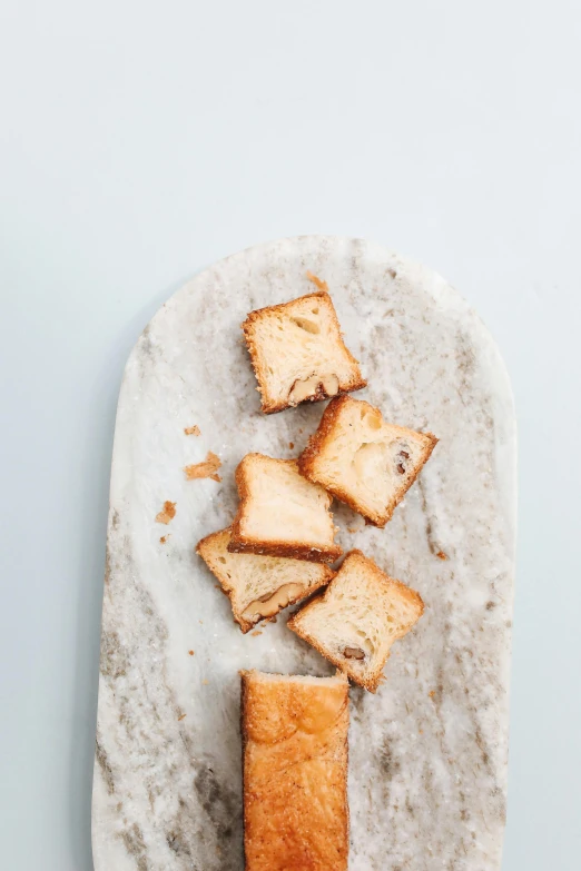 a piece of bread sitting on top of a white plate, unsplash, baroque, squares, on a pale background, dessert, standing still